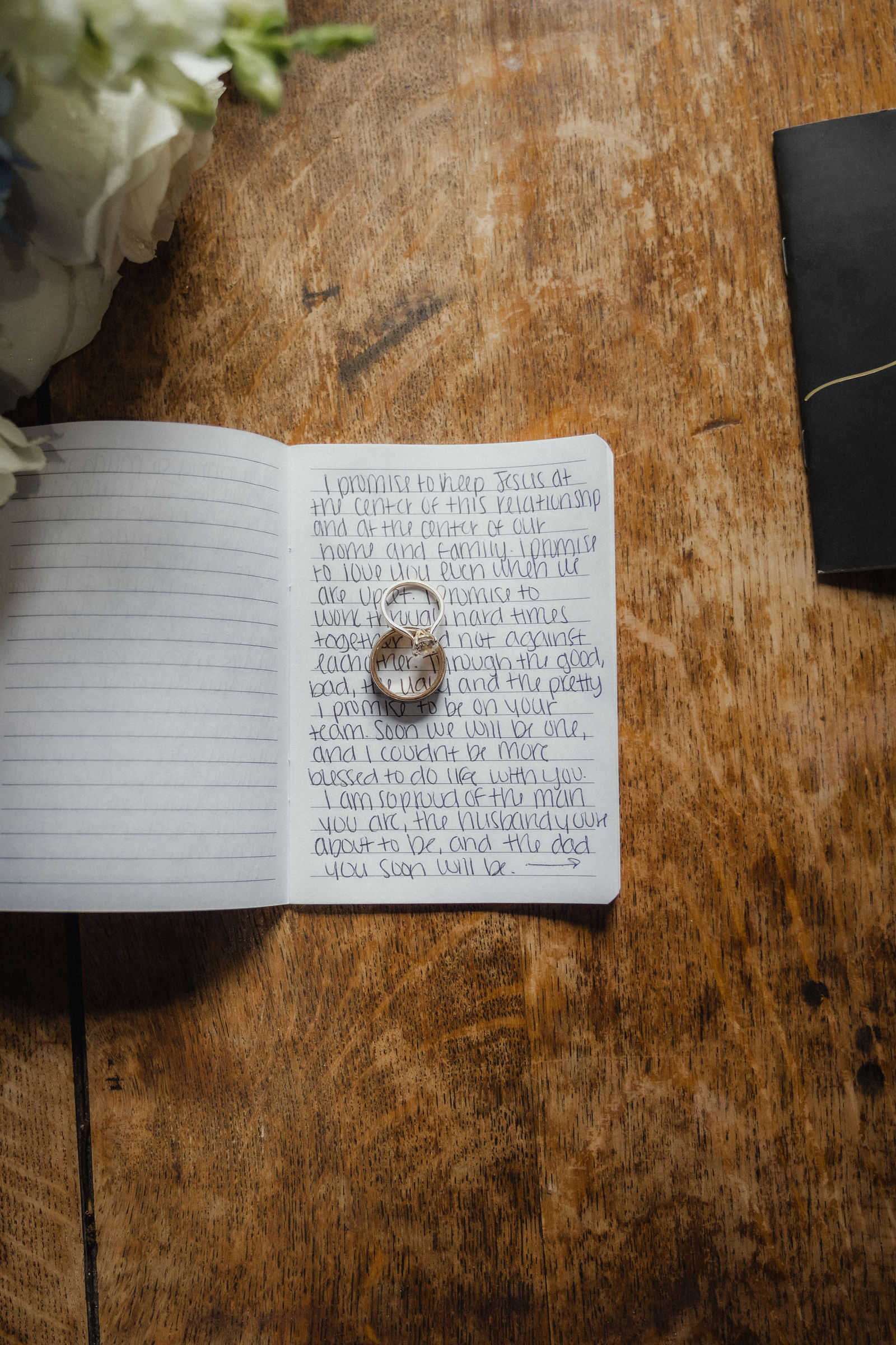Handwritten vows in an open notebook with a ring resting on the page