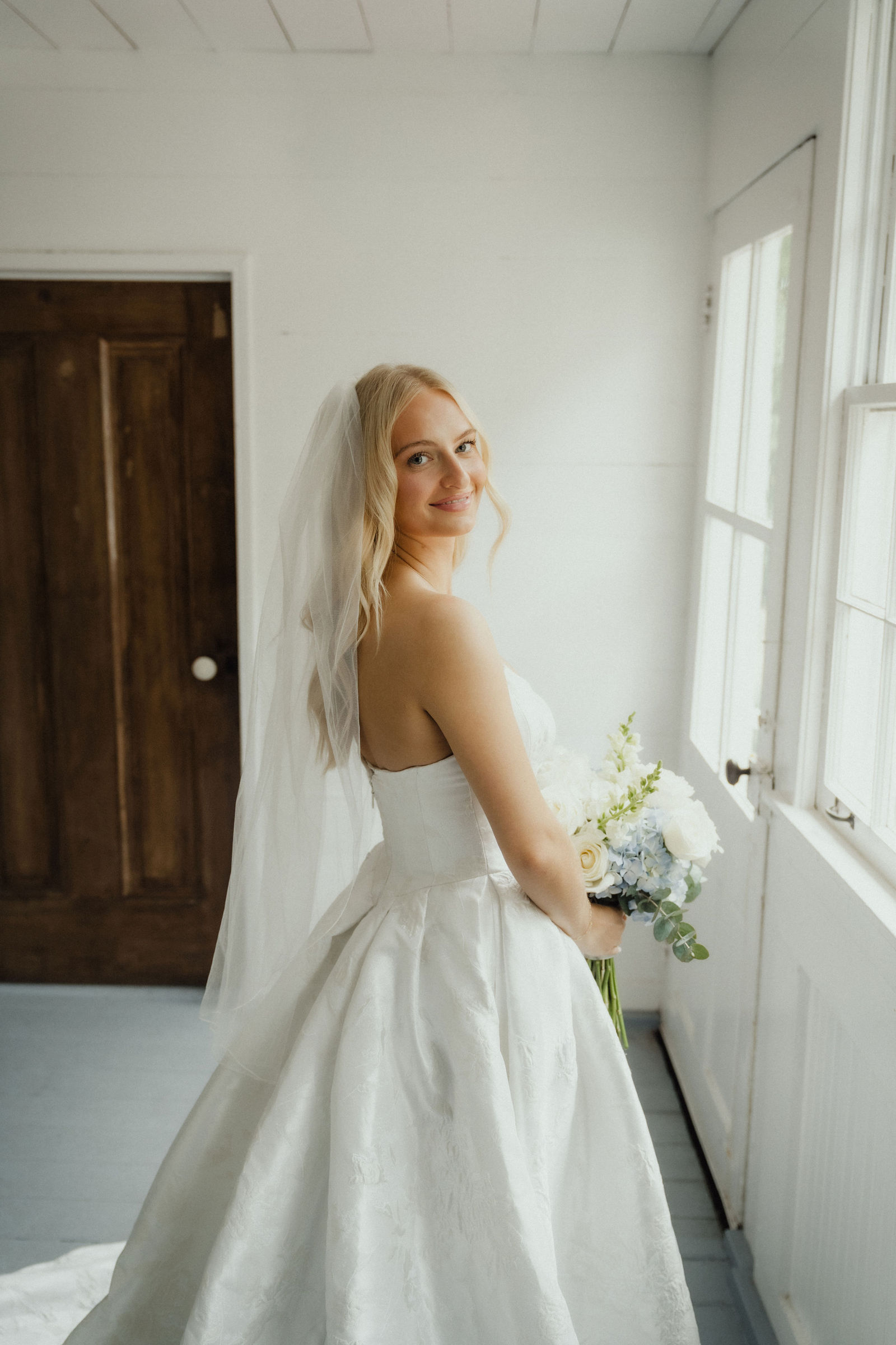 Denalyn with her bouquet in the white room, light coming in from the side