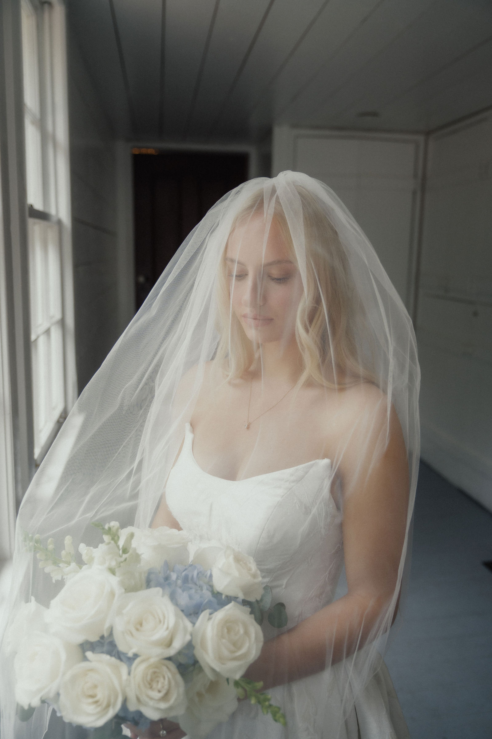 Denalyn under her veil holding the blue and white bouquet
