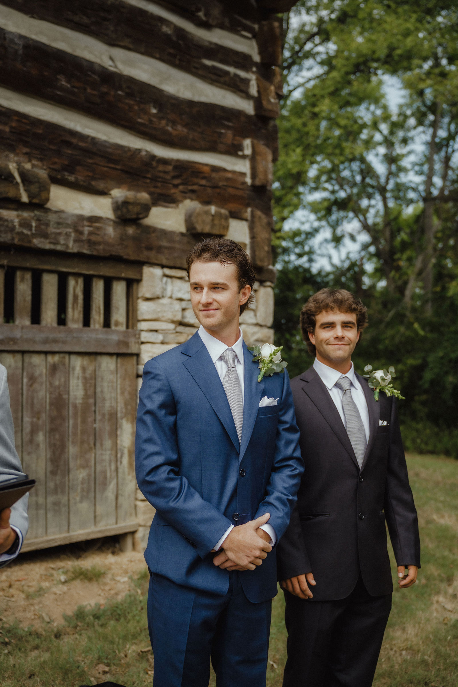 John and his best man waiting against the log wall
