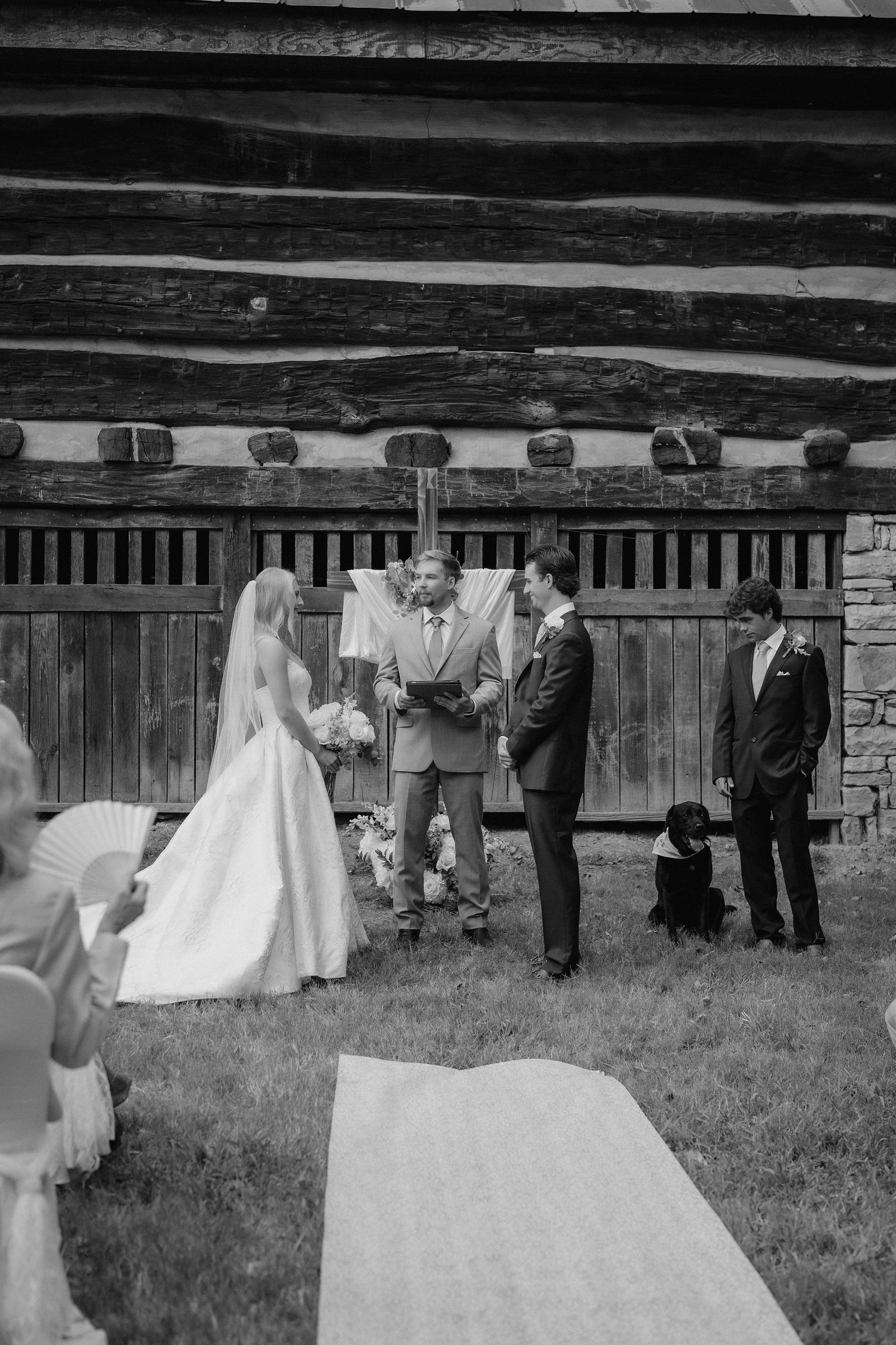 The ceremony in black and white, their black Lab sitting beside them at the altar
