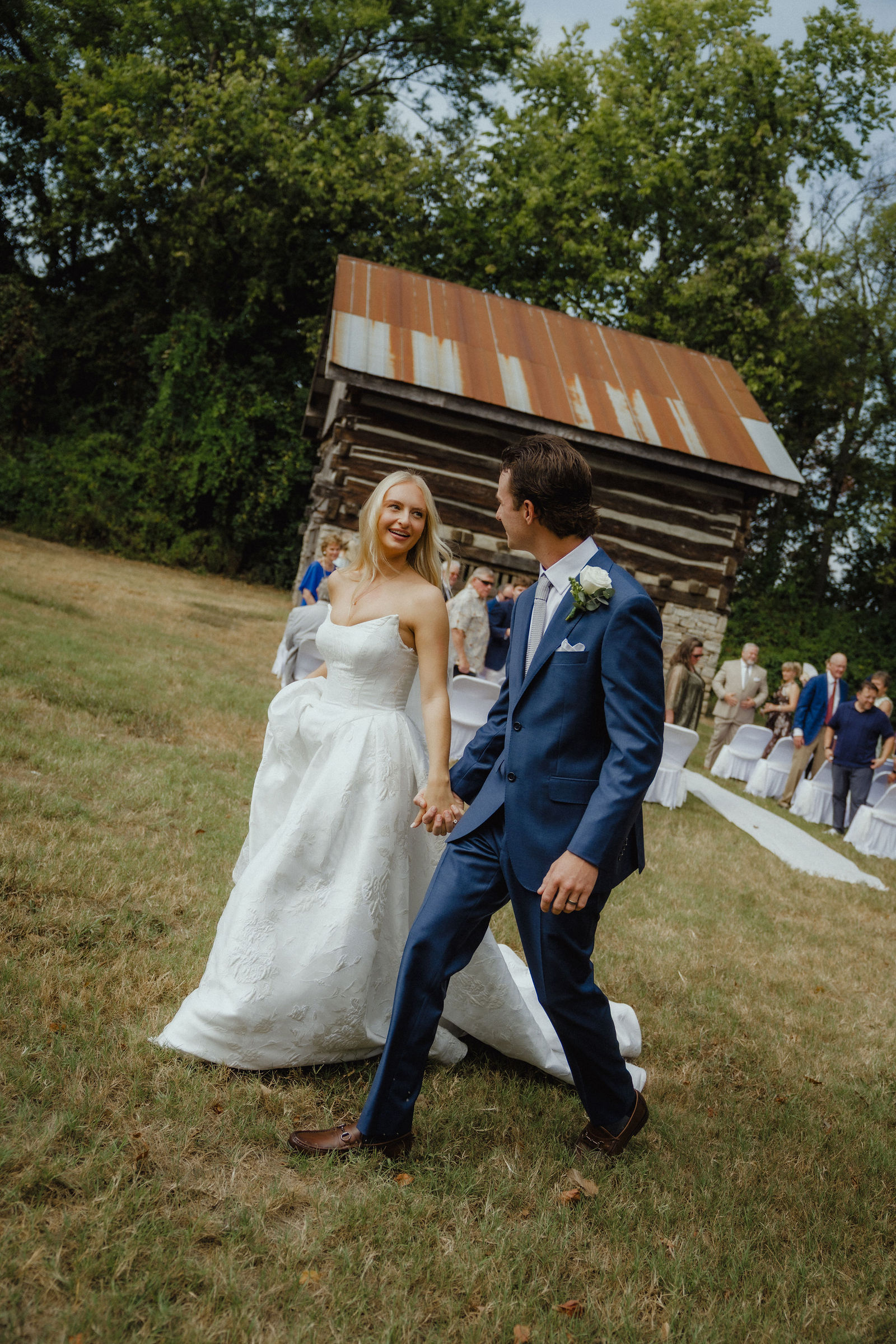 Denalyn and John walking back up the lawn, the log cabin behind them