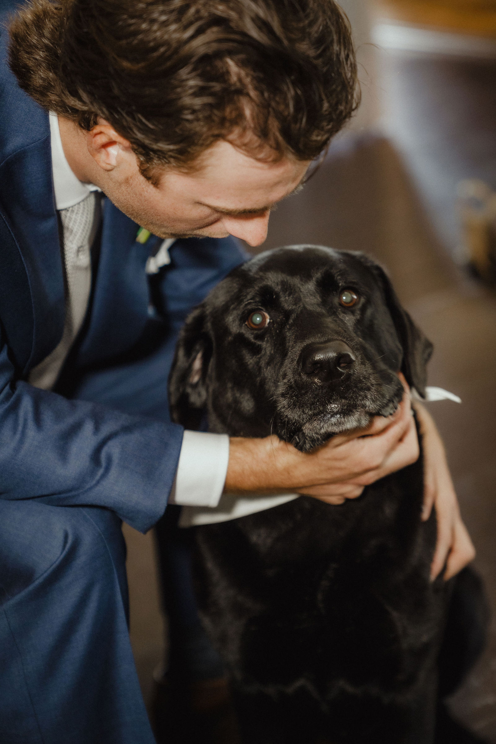 John with his arms around their black Lab at the reception