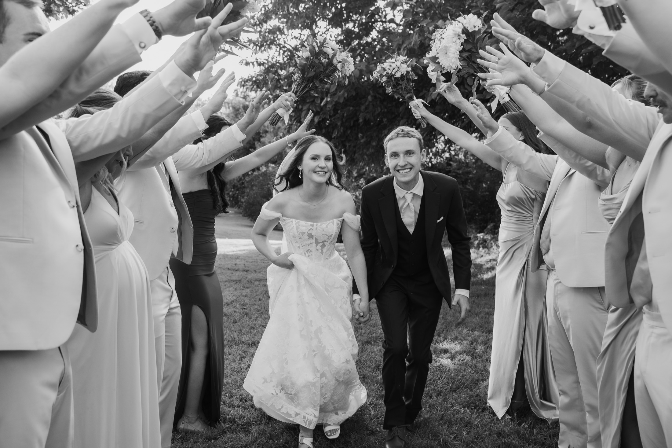 Katie and Zach running through a tunnel made by their wedding party