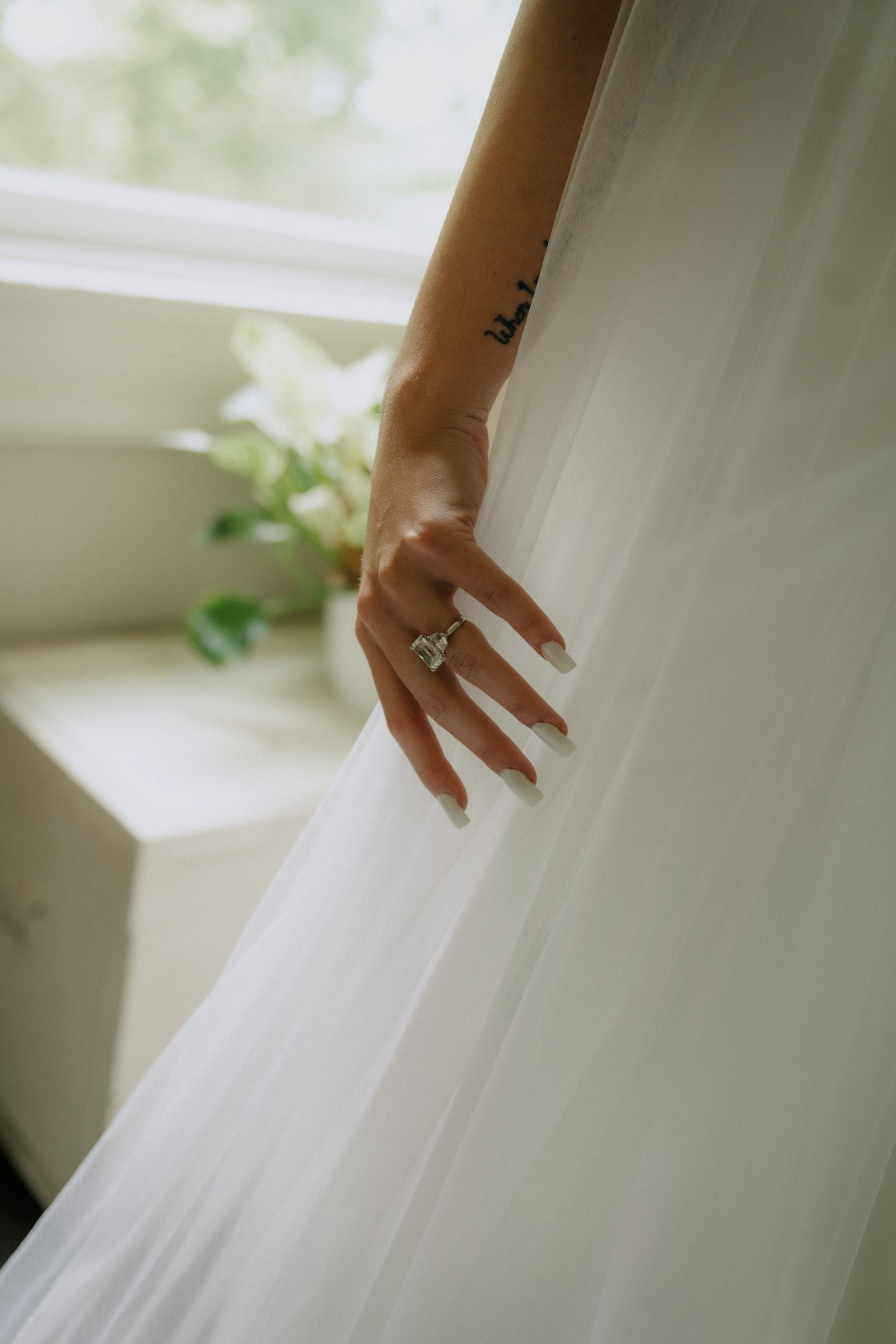 Maddie’s ring and bouquet against her veil in the window light
