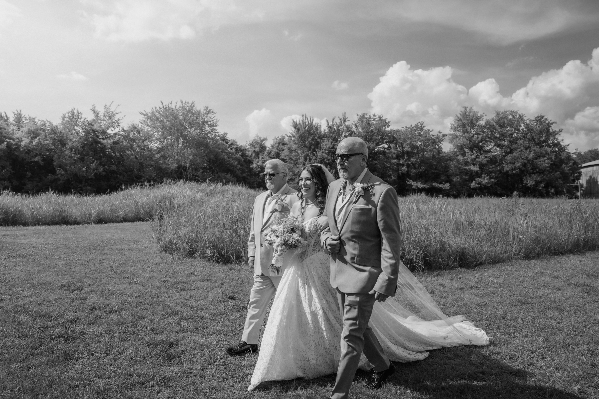 Presley walking through the field with her parents in black and white