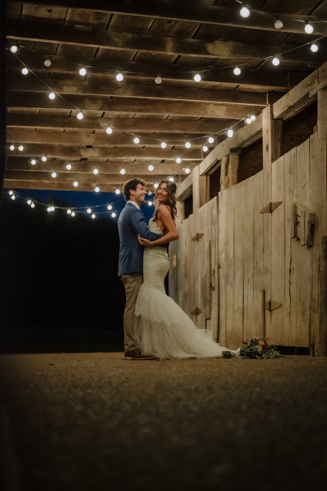 The interior of the historic barn at Drakewood Farm lit by hanging string lights